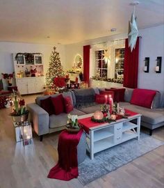 a living room decorated for christmas with red and grey furniture, candles and decorations on the coffee table