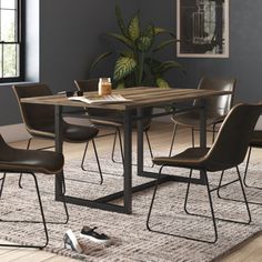 a dining room table with four chairs and a rug on the floor in front of it