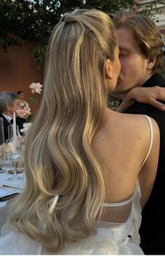 a man and woman kissing each other in front of a table with white flowers on it