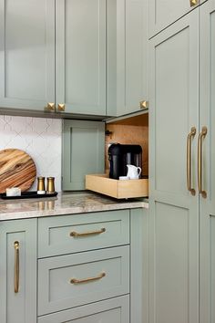 a kitchen with green cabinets and gold handles