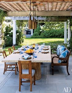 an outdoor dining table with blue and white dishes on it is surrounded by greenery