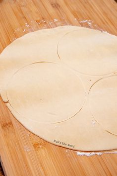 three pizza dough circles on a wooden cutting board