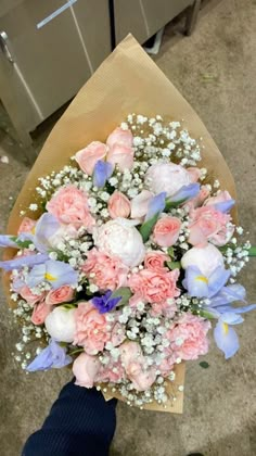 a person holding a bouquet of flowers in their hand on the ground next to an oven