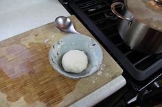 a bowl filled with food sitting on top of a wooden cutting board next to a stove