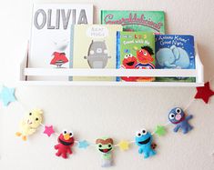 a shelf with books and magnets on it in the shape of sesame street characters