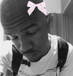 a man with a pink bow tie on his head looking down at something in front of him