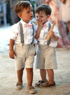 two young boys standing next to each other wearing suspenders and bow ties with their hands together