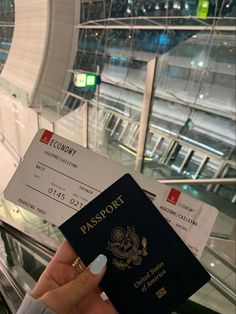 someone is holding up their passport and it's boarding pass in front of an escalator