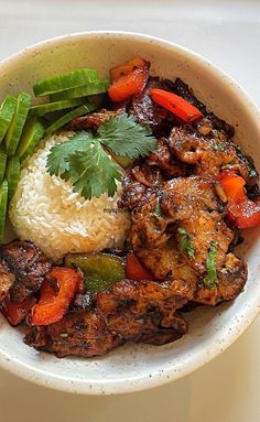 a white bowl filled with meat, rice and veggies on top of a table