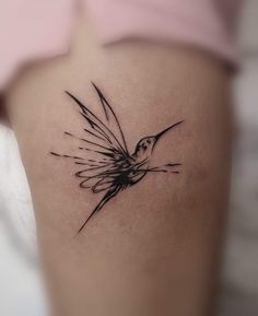 a small black and white bird tattoo on the back of a woman's thigh