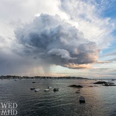 several boats floating in the water under a cloudy sky