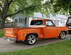 an orange truck is parked on the side of the road in front of a house