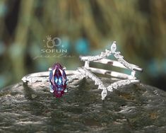 two silver rings with green and white stones on top of a stone slab in front of a blurry background