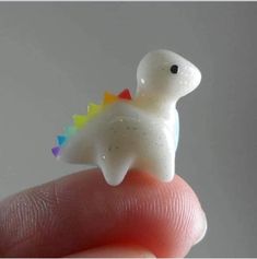 a tiny toy dinosaur sitting on top of a finger