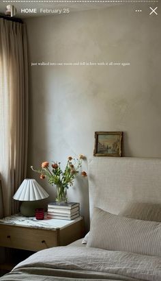 a bed with white sheets and pillows next to a lamp on a table in front of a window