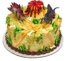 a cake decorated with green and yellow icing has two dinosaurs on top of it