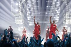 the dancers are performing on stage with their arms in the air and hands raised up