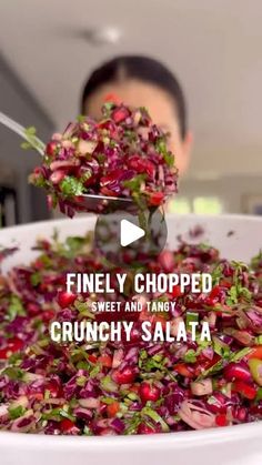 a person is scooping some food out of a large white bowl with red cabbage and pomegranates