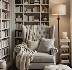 a living room filled with lots of bookshelves next to a chair and lamp