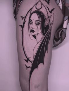 a woman's leg with a bat and moon tattoo design on the side of her thigh