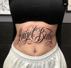 a woman's stomach with the words angel baby written on her lower back tattoo