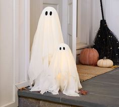 two white ghost statues sitting on the front steps