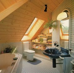 a bathroom with a sink, toilet and bathtub in the corner under a slanted roof