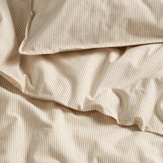 an unmade bed with white and brown striped sheets