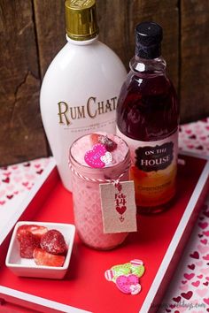 a bottle of rumchat next to a bowl of strawberries on a tray