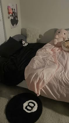 there is a bed with pink sheets and teddy bears on it in the corner, next to a black round rug