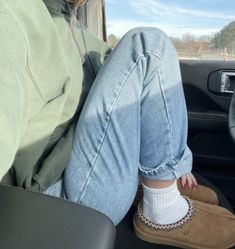 a woman sitting in the passenger seat of a car with her feet on the floor