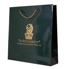 a green shopping bag with the logo of the ritz - carlton company on it