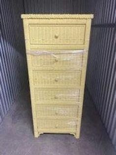 a tall yellow wicker chest of drawers