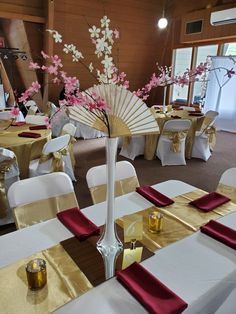 a room filled with tables covered in white and gold cloths, decorated with pink flowers