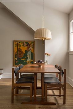 a dining room table with two chairs and a painting on the wall