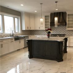 a large kitchen with marble counter tops and white cabinets, along with an island in the middle