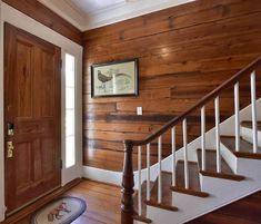 an entryway with wood paneling and white railings is shown in this house