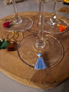 three wine glasses with tassels are sitting on a wooden board and ready to be filled