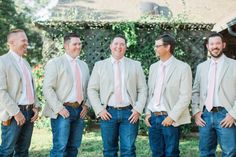 a group of men standing next to each other in front of a house with pink ties