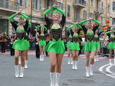 a group of women in green outfits are marching down the street