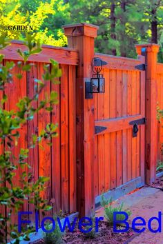 an orange wooden fence with the words flower bed on it and trees in the background