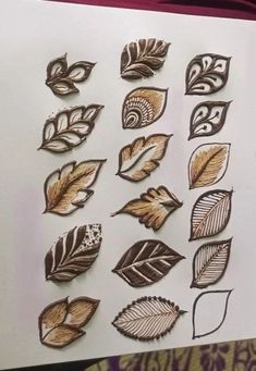 a bunch of different types of leaves on a piece of white paper with gold foil