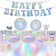 a birthday party set up with silverware, plates and utensils on a holographic table cloth