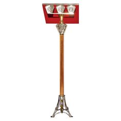 a red and gold metal floor lamp with three lights on it's sides, in front of a white background