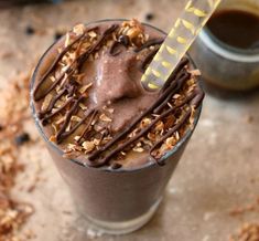 there is a chocolate drink with nuts on the rim and a straw sticking out of it