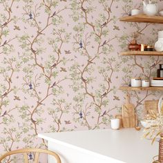 the wallpaper in this kitchen is pink and has birds on it, as well as branches