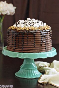 a chocolate cake topped with marshmallows on a green plate next to flowers