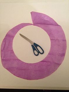 a pair of scissors sitting on top of a piece of purple paper next to a pink circle