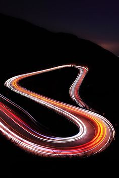 an aerial view of a highway at night with long exposure and light trails on the road