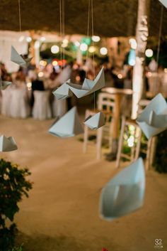 a group of people standing around a room filled with tables and white cloths hanging from the ceiling